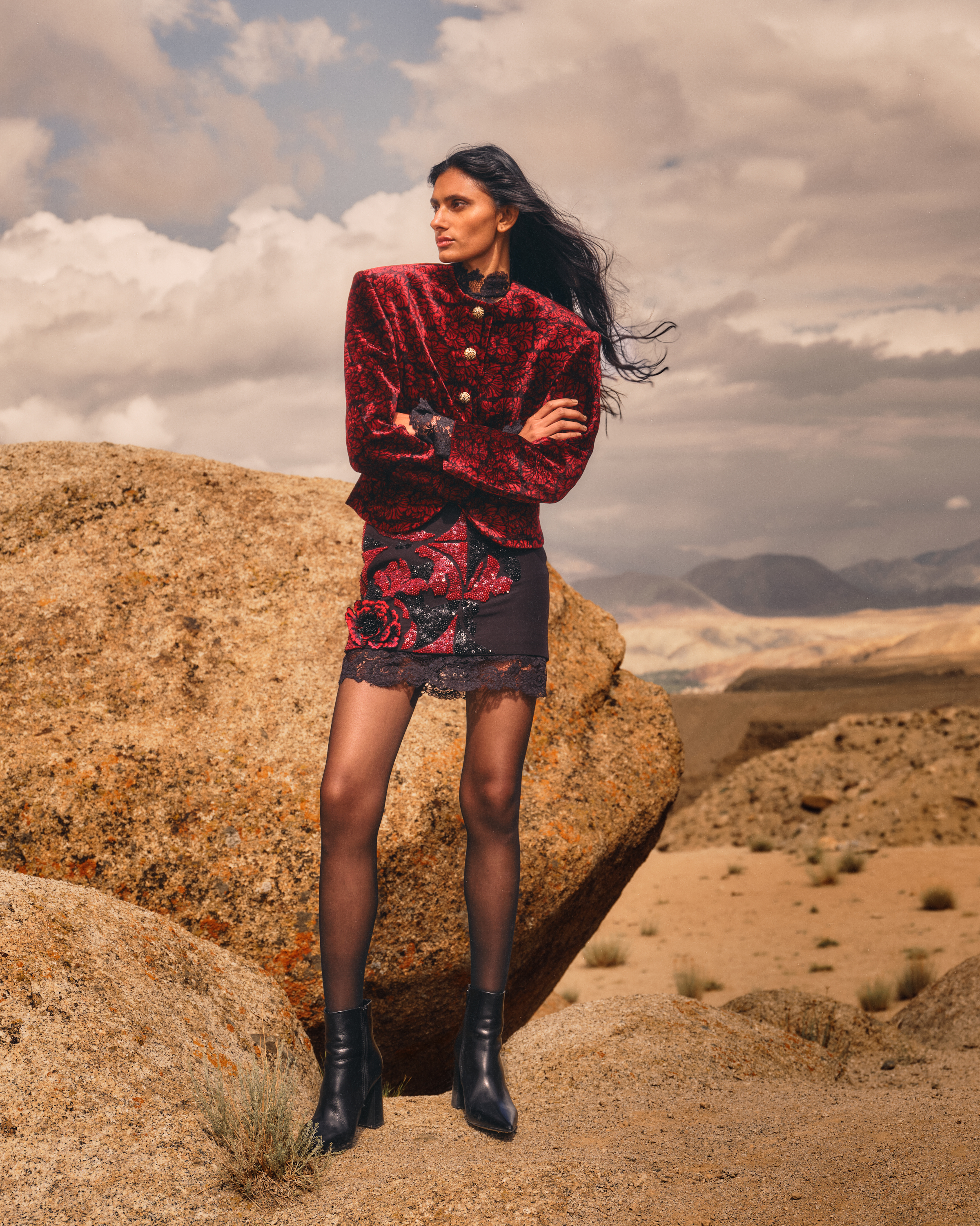 Model wearing a red patterned jacket and embroidered skirt in Āroka’s The Ascent campaign