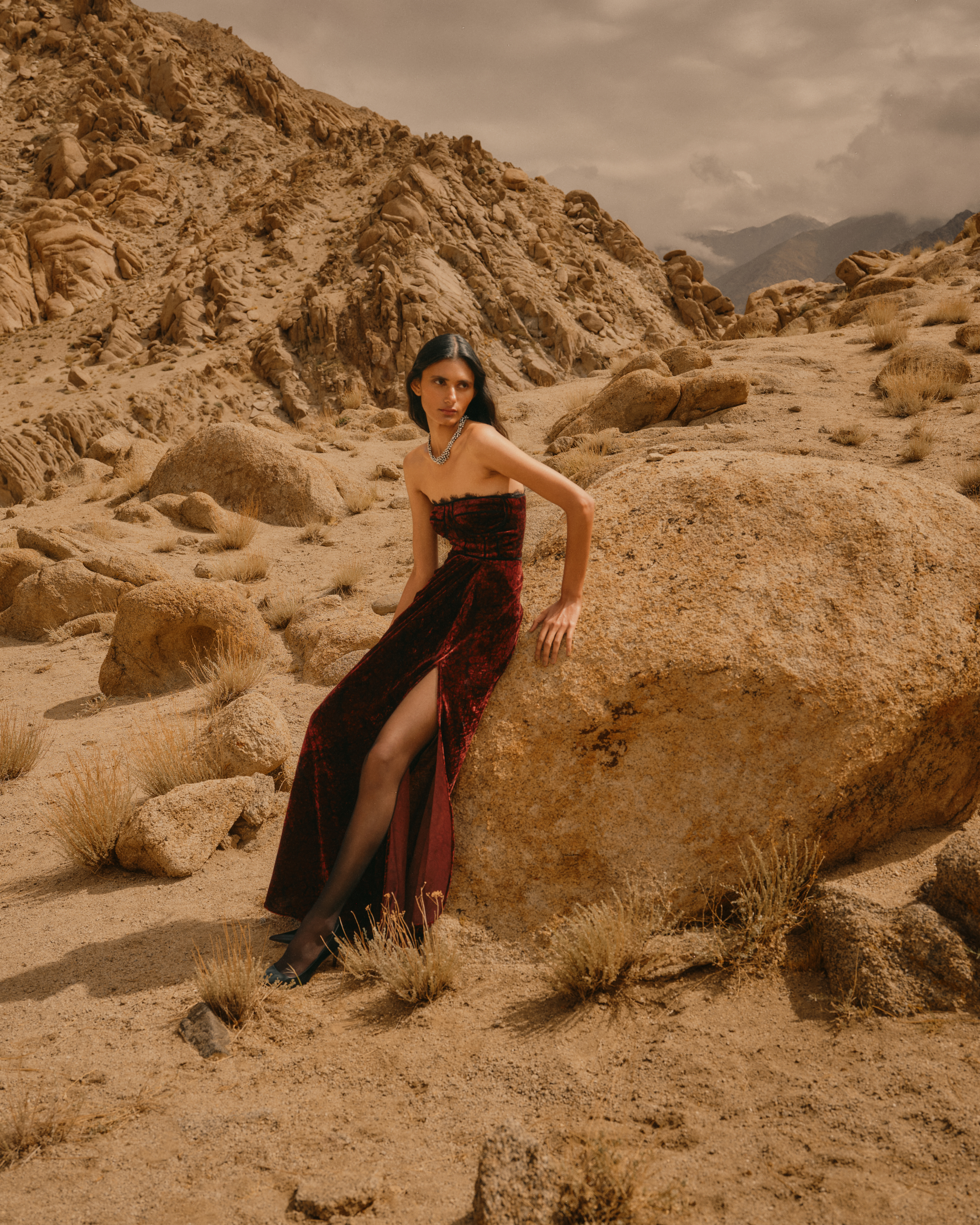 Model wearing a strapless burgundy gown from Āroka’s The Ascent amid Ladakh’s rocky landscape