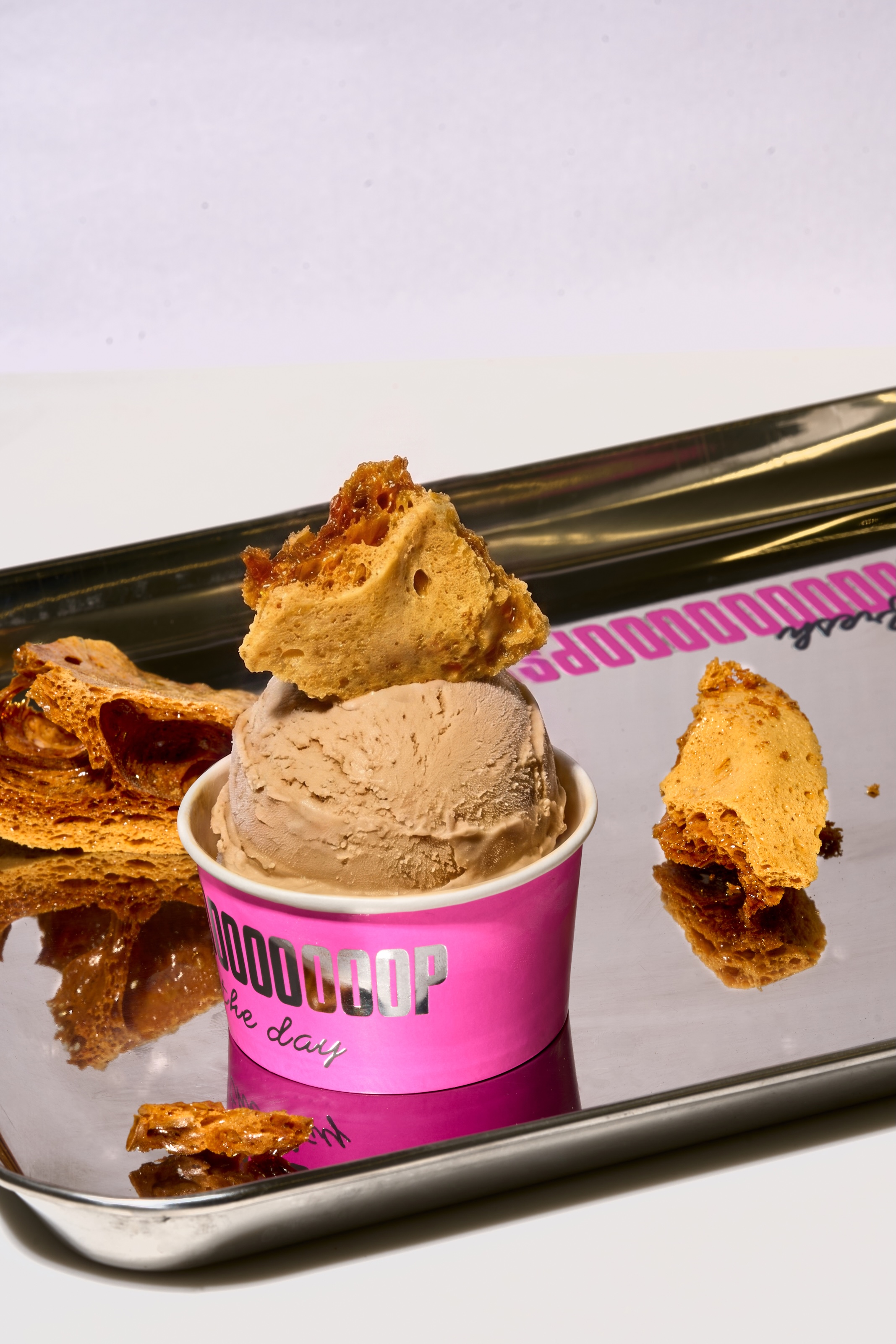Ice cream topped with honeycomb pieces in a pink Scoop Room cup