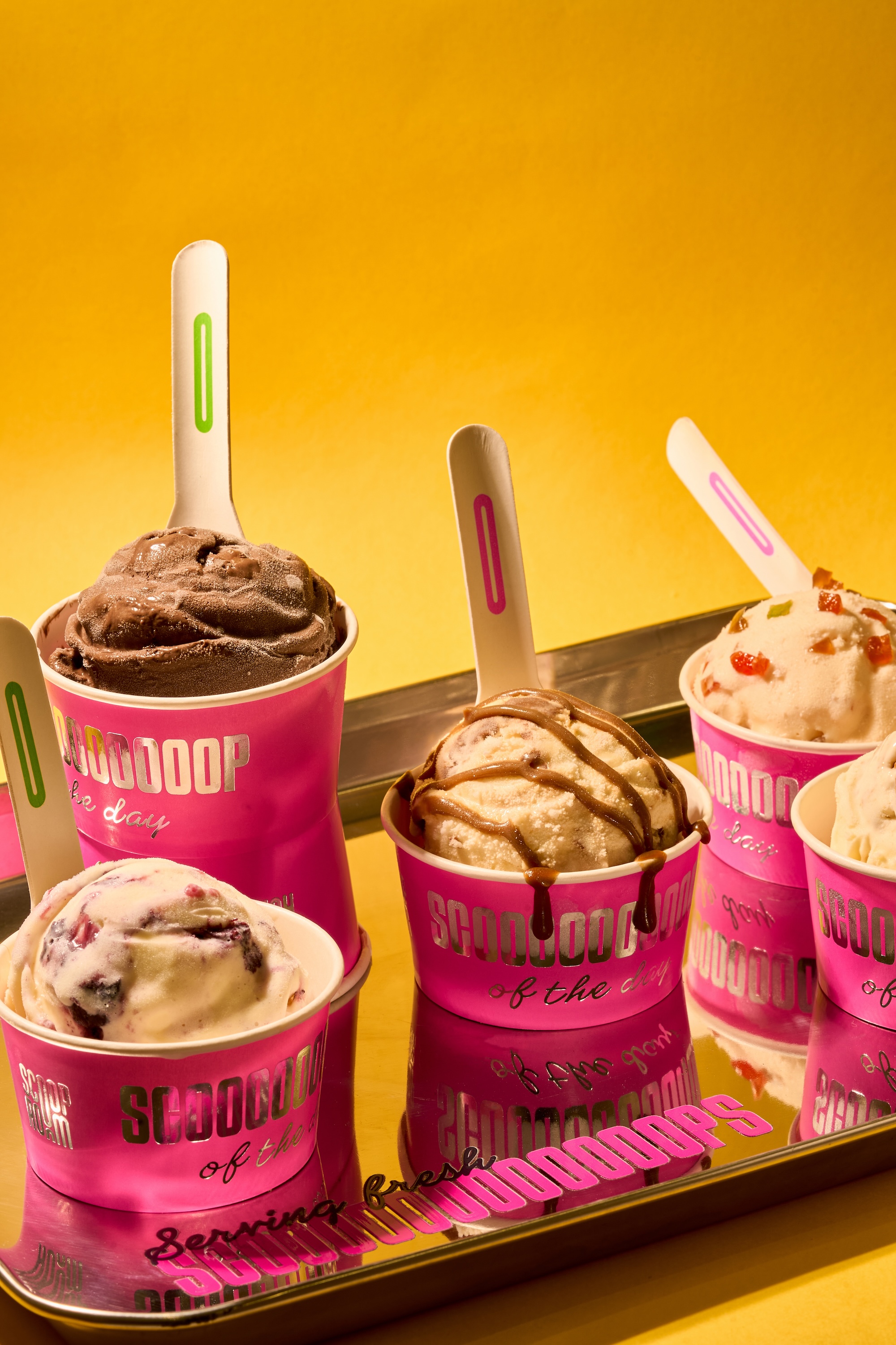 Assorted ice cream scoops in pink Scoop Room cups on a silver tray