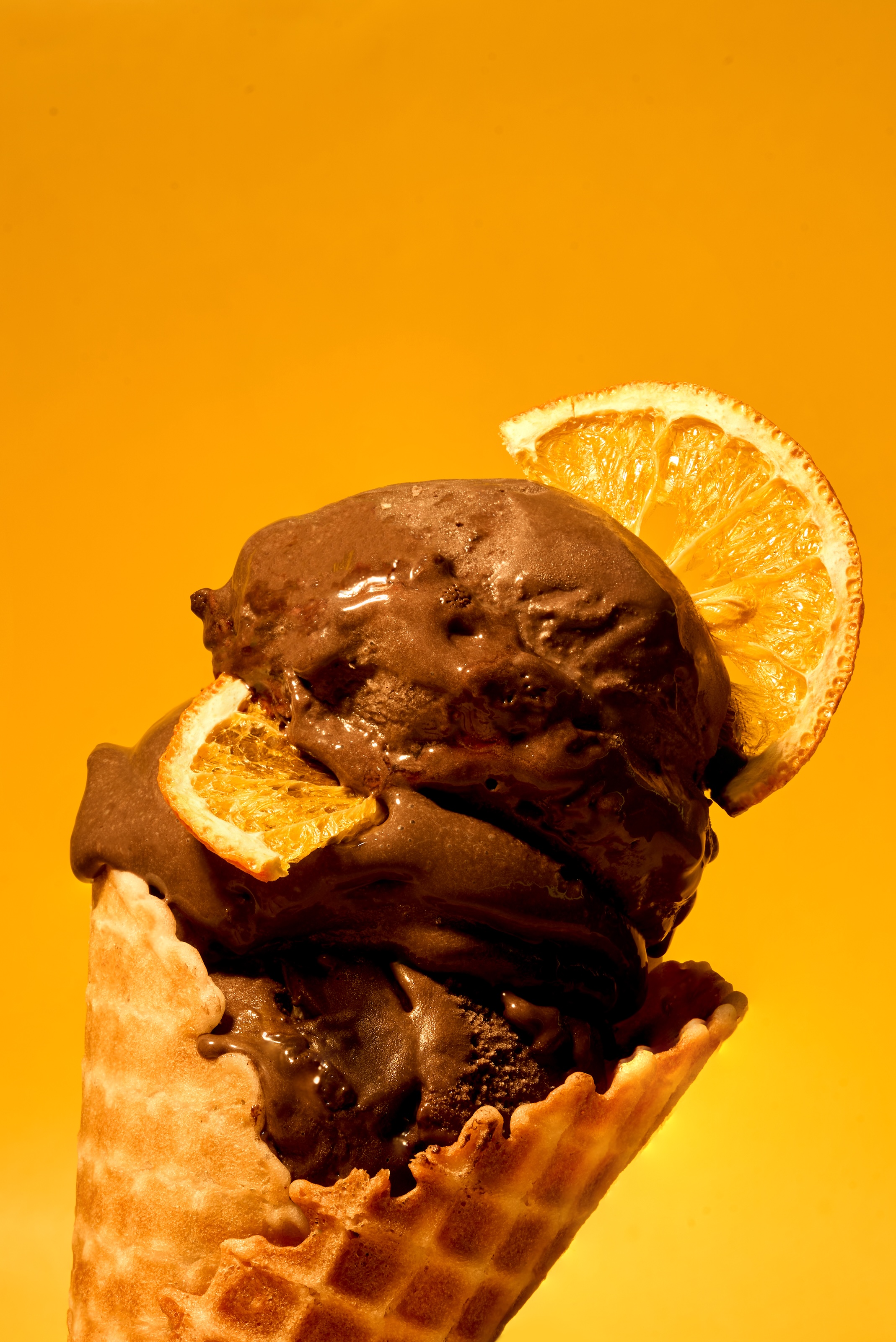 Dark chocolate orange ice cream in a waffle cone with orange slices