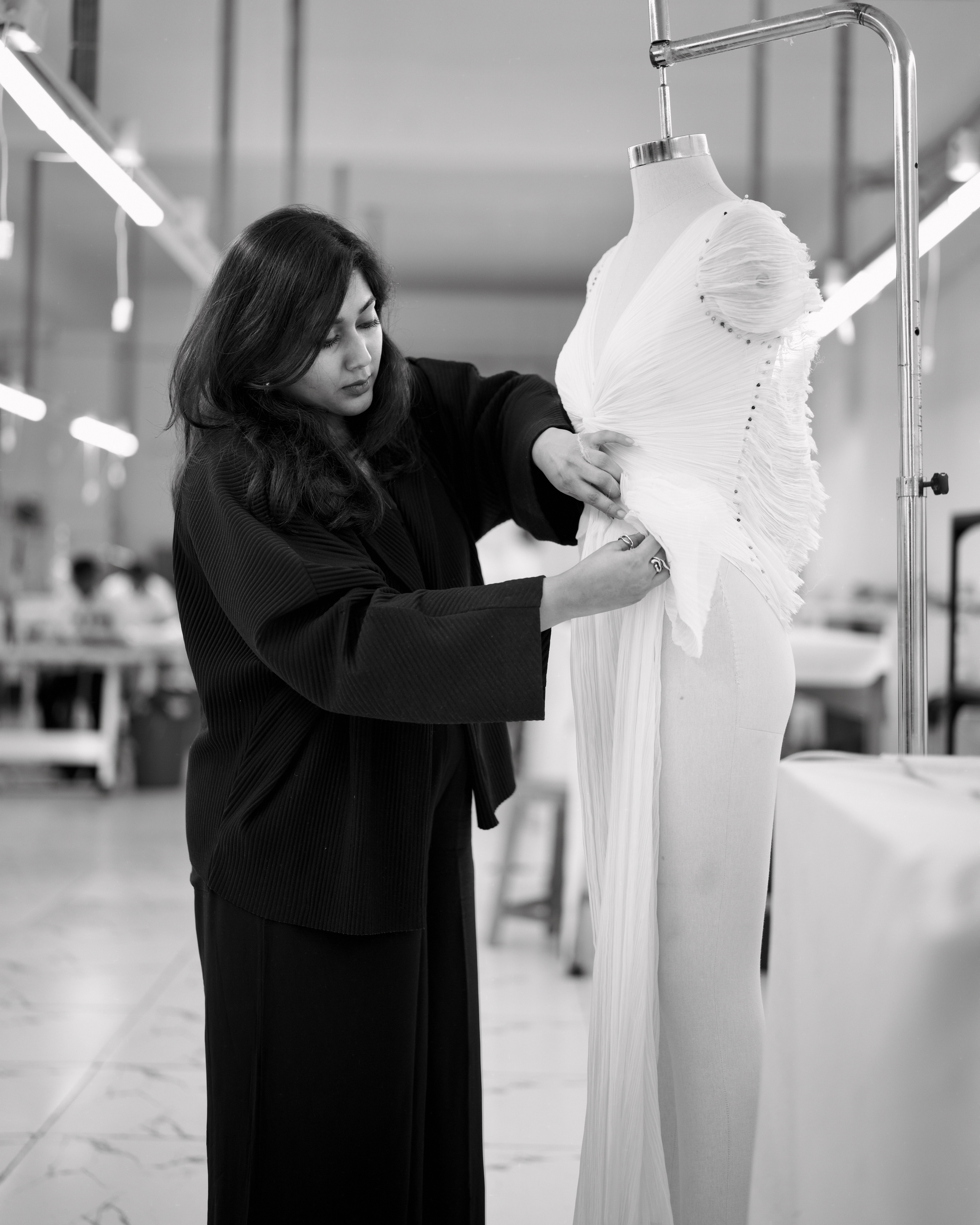 Shweta Agarwal shaping white draped fabric on a dress form in her studio