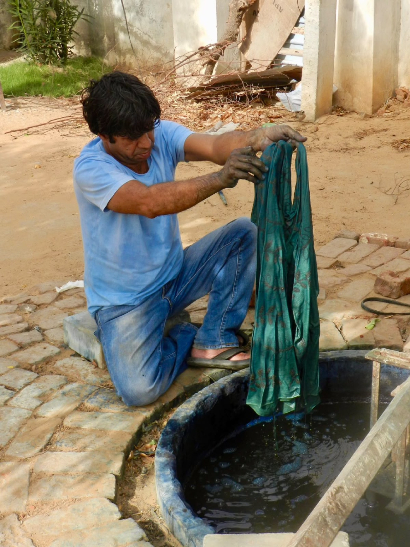 Craftsperson lifting fabric from a dye vat