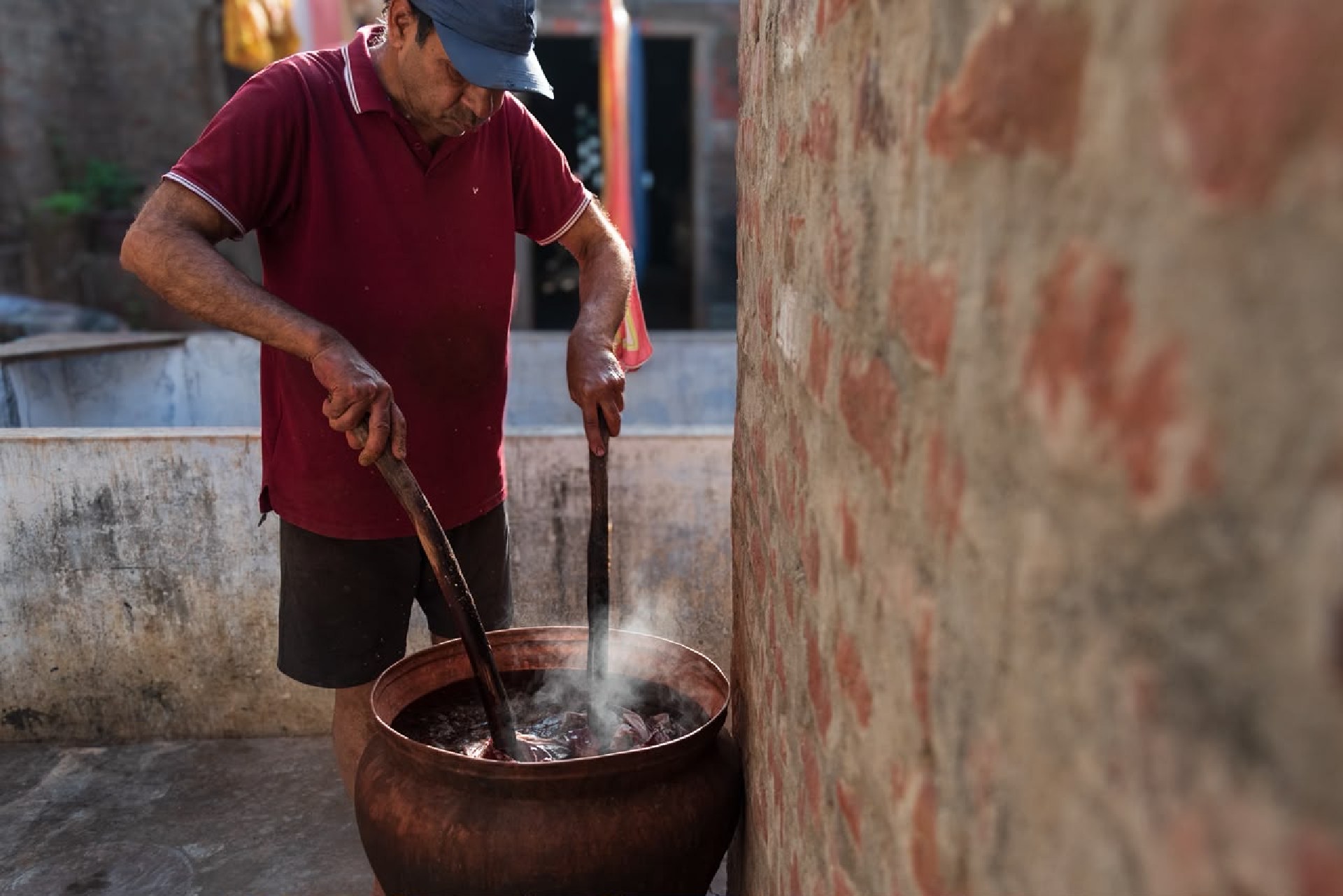Craftsperson stirring cloth in a steaming dye vessel