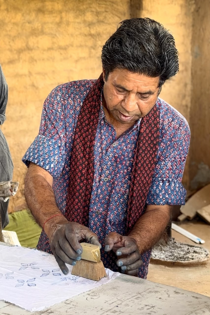 Artisan applying a wooden printing block to white cloth