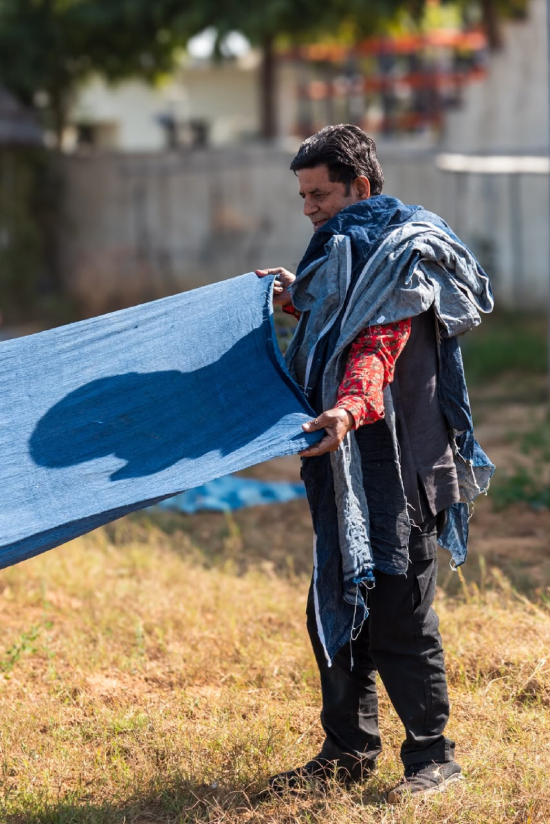 Craftsperson holding a length of blue fabric outdoors