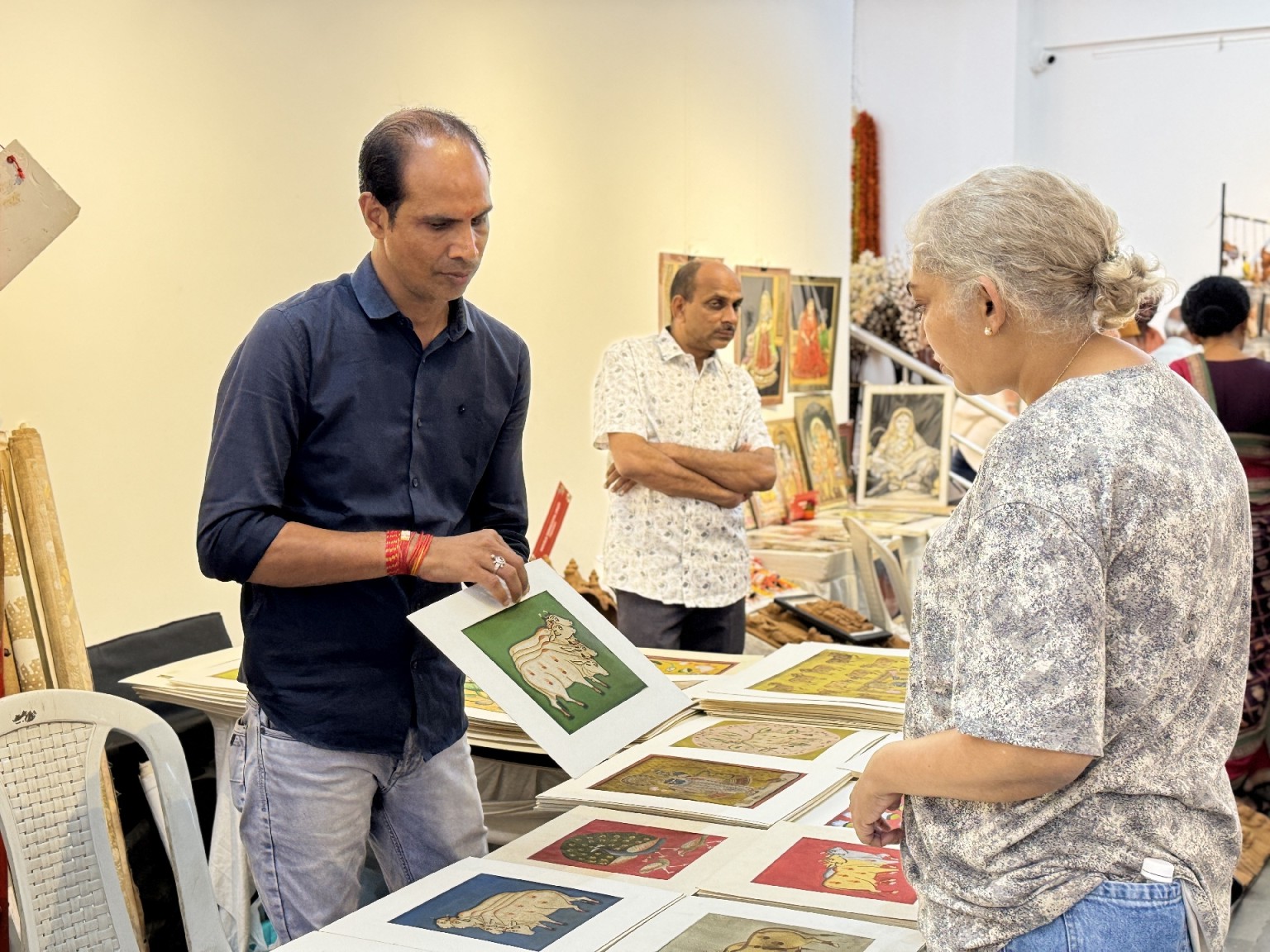 A visitor exploring folk paintings at a craft exhibition