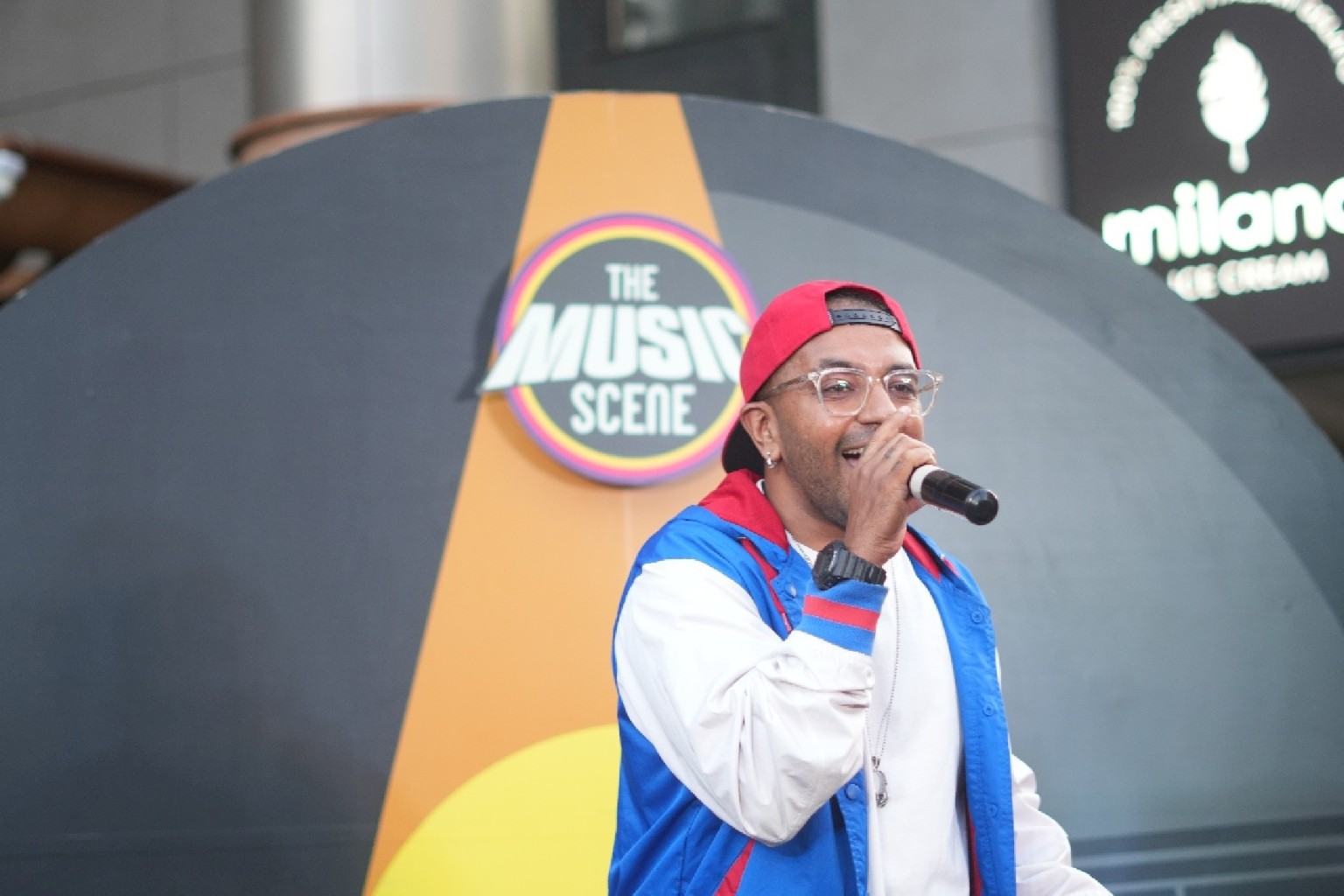 A vocalist performing in front of The Music Scene backdrop